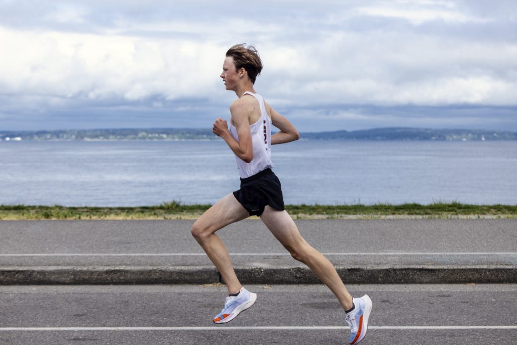 A man participating in the West Seattle 5K, running on a road near a body of water.