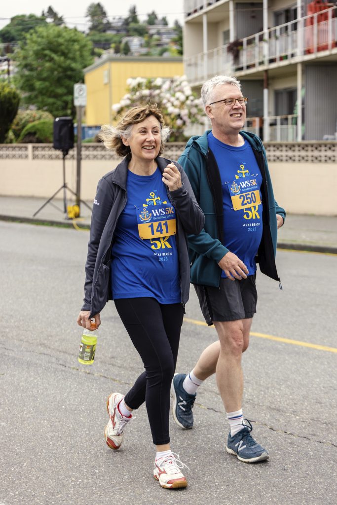 A man and a woman participating in the West Seattle 5K walking down the street.