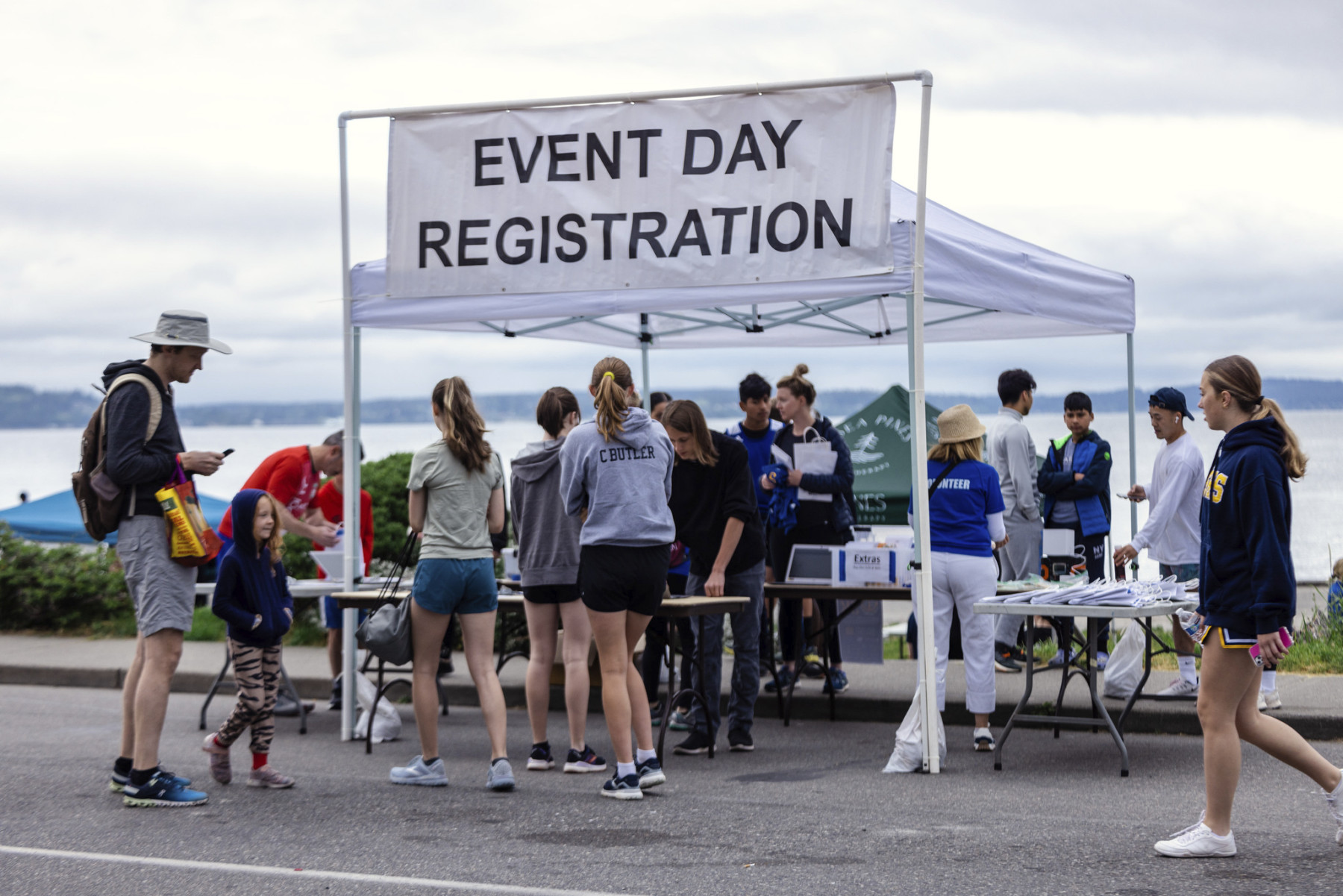 A group of people at the West Seattle 5K standing in front of a sign that says event day registration.