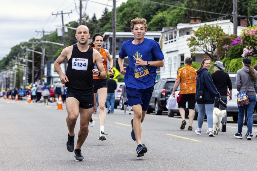 A group of people participating in the West Seattle 5K race on a street.
